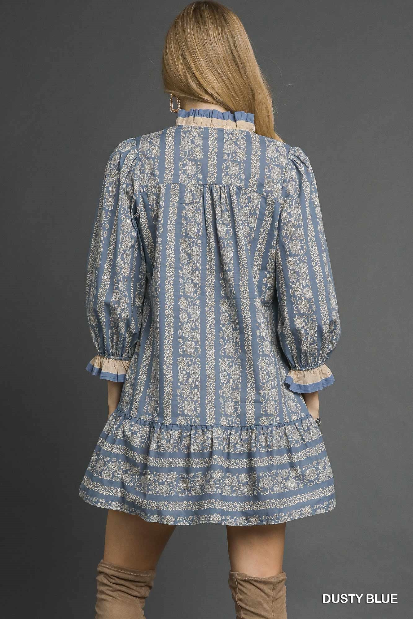 Woman wearing a blue and white patterned dress with long sleeves on a gray background